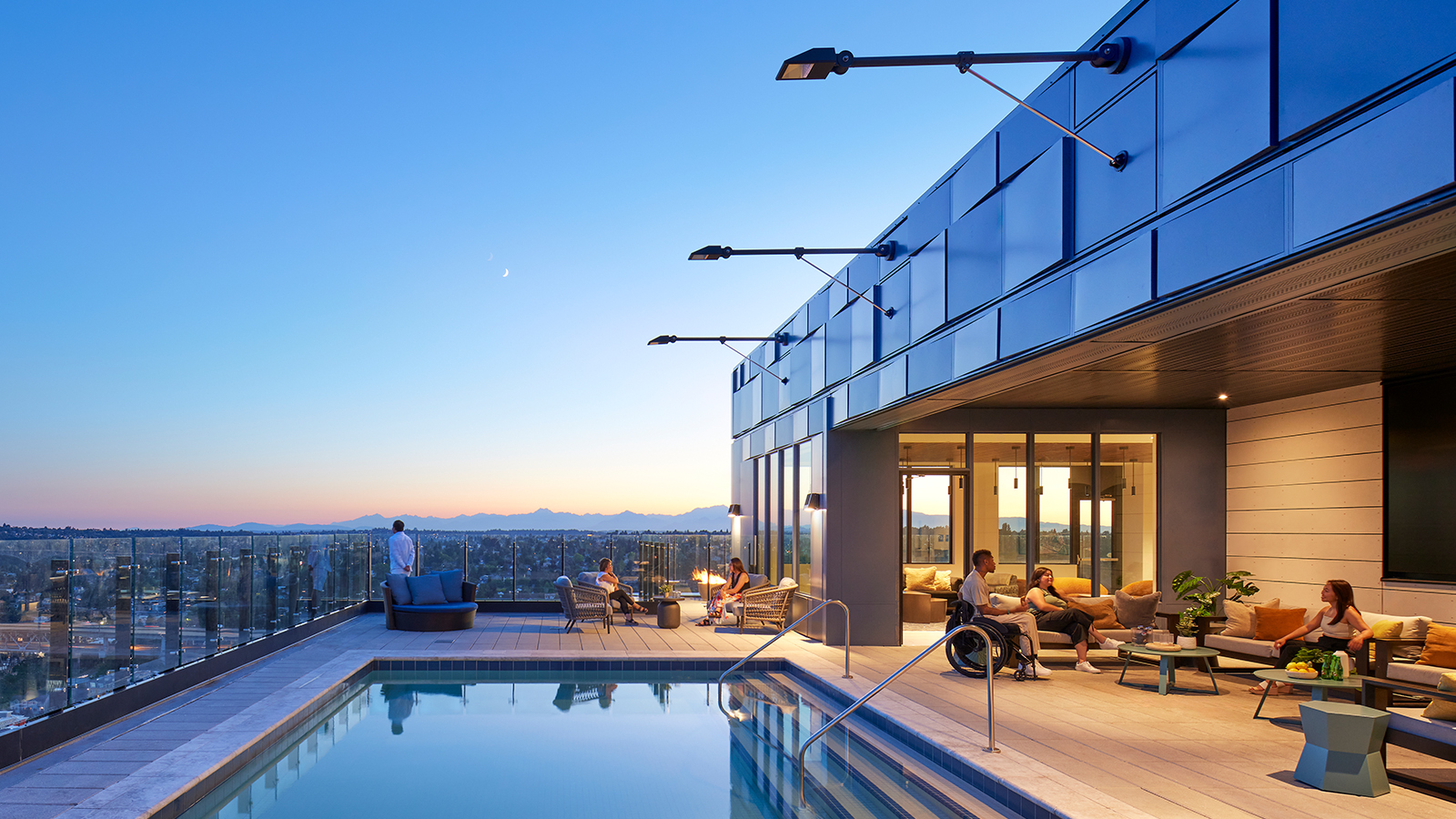 Rooftop pool with people sitting, talking, and enjoying the city views.